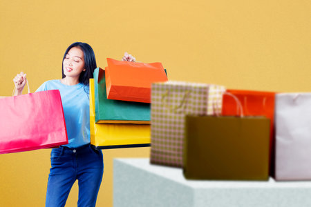 Asian woman carrying shopping bags standing with a colored backgroundの写真素材