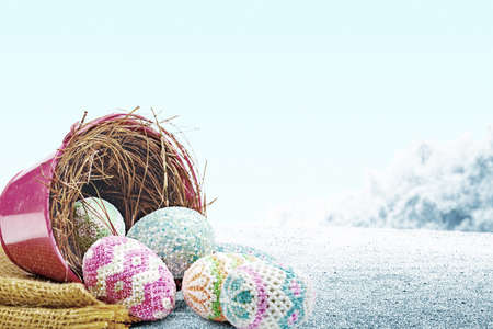 Colorful easter eggs spilled from the nest in a red bucket with fabric on the field. Happy Easterの写真素材