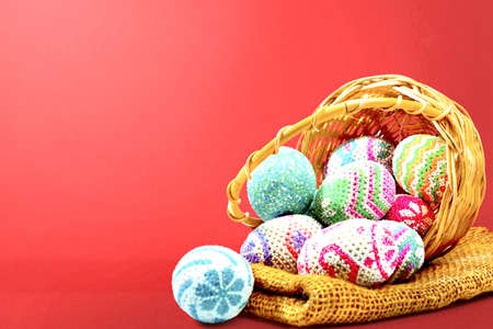 Colorful easter eggs spilled from the wooden basket with fabric on a colored background. Happy Easterの写真素材