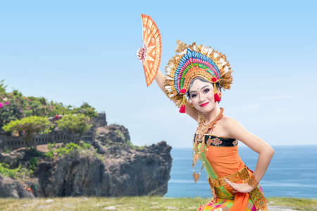 Asian woman dancing Balinese traditional dance (Kembang Girang dance) on the cliff
