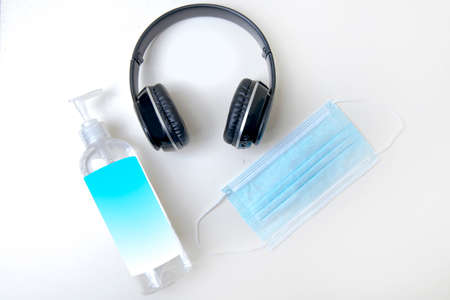 Black headphone, face mask and hand sanitizer isolated over white backgroundの写真素材