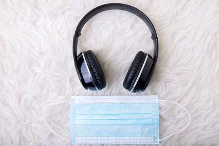 Black headphones and face mask on the white carpetの写真素材