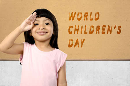 Asian cute girl with a funny expression standing with world children's day text on the wall. World Children Dayの写真素材