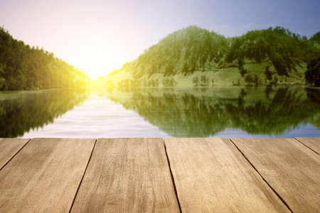 Wooden terrace with lake and hill view with sunlight backgroundの写真素材