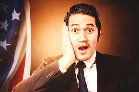Asian businessman standing with an American flag with a bright background. Fourth of July Concept