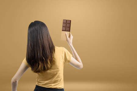 Rear view of Asian woman holding the chocolate bar with brown background