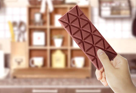Human hand holding the chocolate bar with blurred background