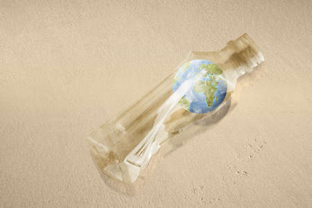 Earth in a plastic bottle on the sandy beach. Plastic pollutionの写真素材
