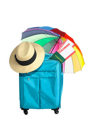 Blue suitcase, hat, ticket, and passport with umbrella isolated over white backgroundの写真素材