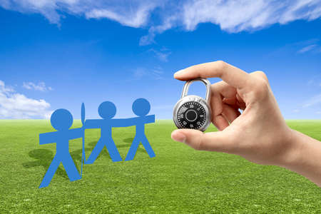 Human hand holding padlock with blue sky backgroundの写真素材