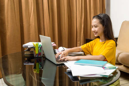 Asian little girl doing her homework with laptop at home. Online education during quarantine
