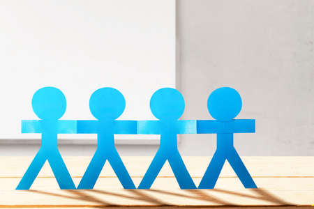 Blue people paper holding hands standing with wall and window background. World Population Day...