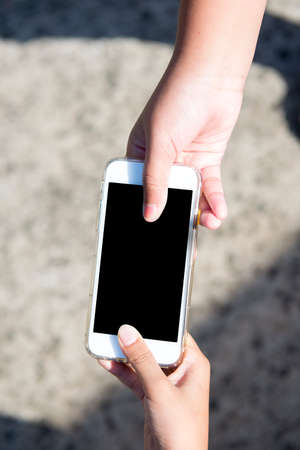 Hand giving mobile phone with blurred background