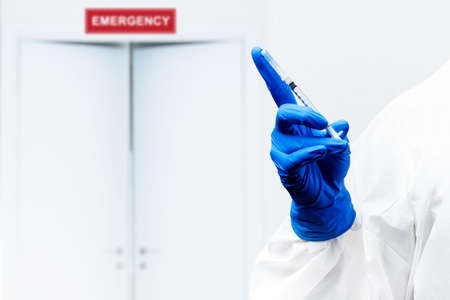 Health worker woman with a protective suit and gloves holding covid 19 vaccines on the hospital