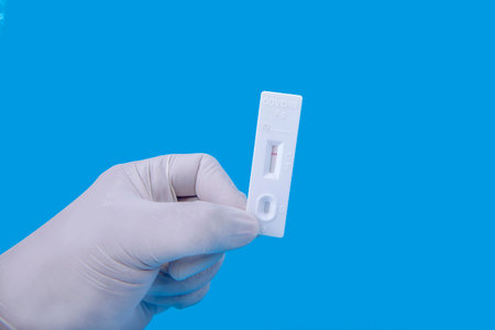Health worker hand with protective gloves holding  antigen test kit with colored background
