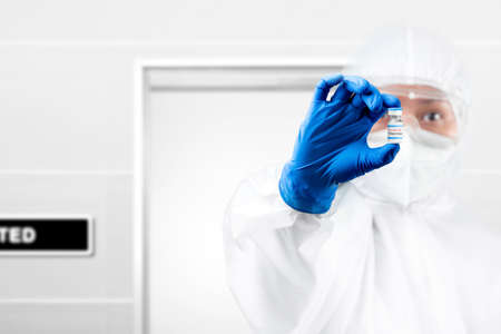 Health worker woman with a protective suit and gloves holding  vaccines on the hospitalの写真素材