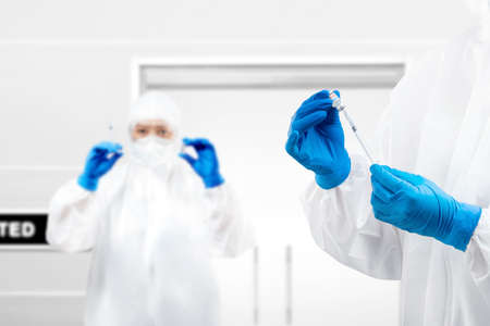 Health worker woman with a protective suit and gloves holding  vaccines on the hospitalの写真素材