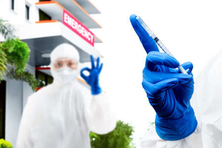 Health worker woman with a protective suit and gloves holding covid 19 vaccines on the hospital