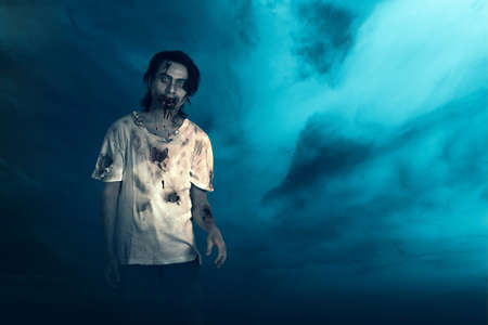 Scary zombie with blood and wound on his body standing with a night scene background