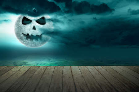 Wooden table with Jack-o-Lantern on the dark cloudscapes on the nightの写真素材