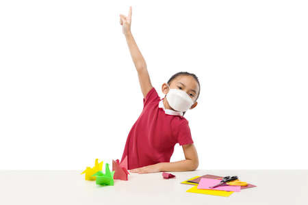 Asian little girl wearing the mask pointing something isolated over white background
