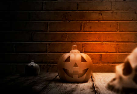 Jack-o-Lantern on a wooden table with a brick wall backgroundの写真素材