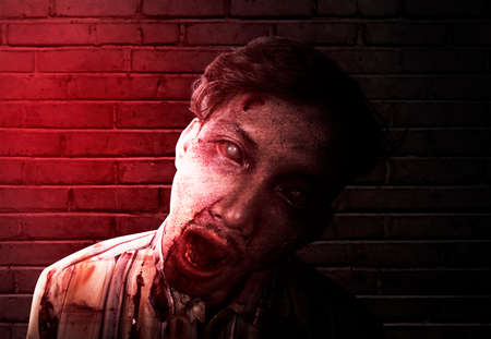 Scary zombie with blood and wound on his body standing in the abandoned buildingの写真素材