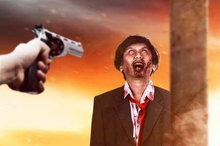 Hand pointing a gun to a zombie. Halloween conceptの写真素材