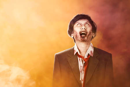 Scary zombie with blood and wound on his body standing with dramatic backgroundの写真素材