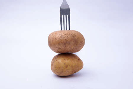 Fork with a stack of potatoes isolated over white backgroundの写真素材