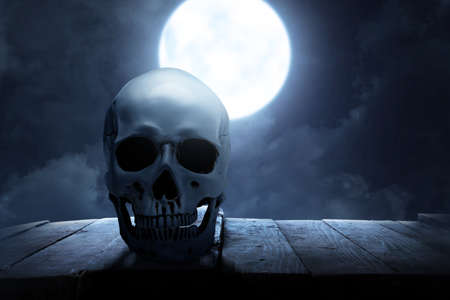 Human skull on wooden table with the night scene backgroundの写真素材