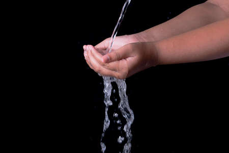 Pouring water splashing on hand with black background