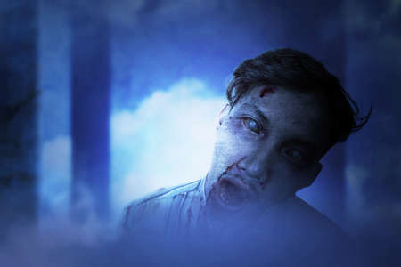 Scary zombie with blood and wound on his body standing in the abandoned building