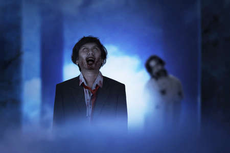 Scary zombie with blood and wound on his body standing in the abandoned buildingの写真素材