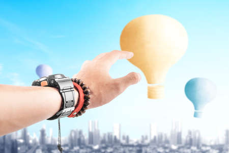 Human hand with colorful air balloon flying with cityscape backgroundの写真素材