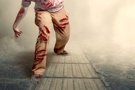 Scary zombie with blood and wound on his body walking with foggy backgroundの写真素材