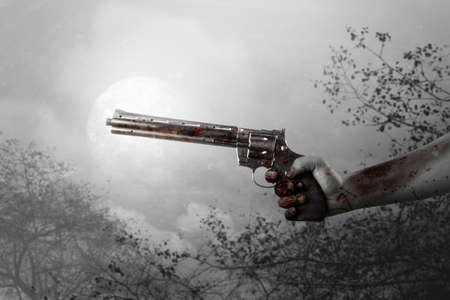 Zombie hands with wound holding a gun with the night scene backgroundの写真素材