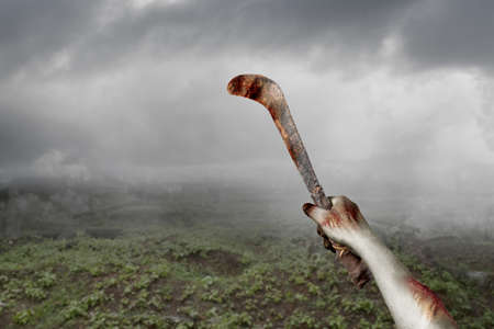 Zombie hands with wound holding sickle on the cemeteryの写真素材