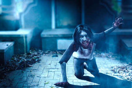 Scary zombie with blood and wound on his body crawling on the cemeteryの写真素材