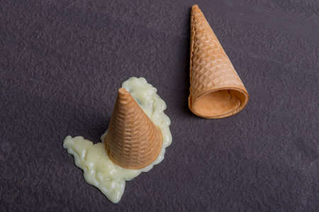 Vanilla ice cream cone melted on black backgroundの写真素材