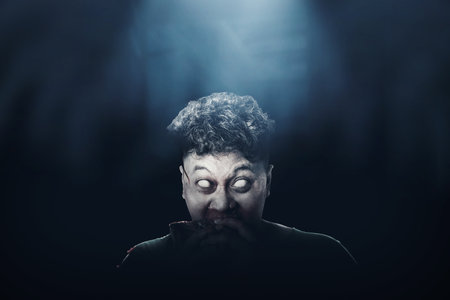 A scary zombie with blood and wound on his body eat the raw meat with dark background