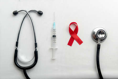 Red ribbon, syringe, and stethoscope with white background. Hiv Aids ribbon awarenessの写真素材