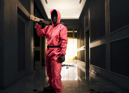 Criminal man in pink guard uniform holding the shotgun while robbery the house
