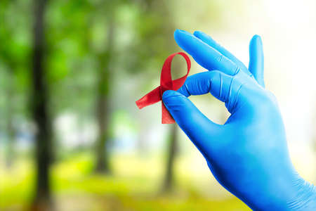 Red ribbon and medical glove with a bright background. Hiv Aids ribbon awarenessの写真素材