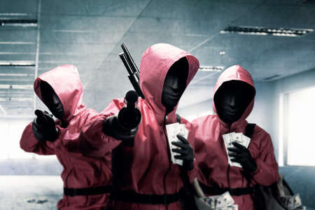 Group of Criminal man in pink uniform and a hidden mask holding the shotgun after the robbery the buildingの写真素材