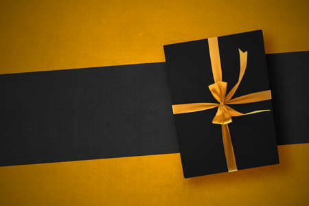 Black gift box with a golden ribbon with a colorful background. Black Friday concept