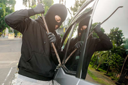 Car thief man with a tool trying to break window car on the streetの写真素材