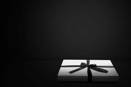 White gift box cap with a black ribbon with a black background. Black Friday conceptの写真素材