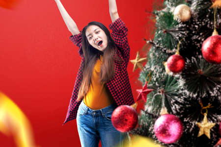 Decorated Christmas tree with Asian woman standing on a colored background. Boxing Dayの写真素材