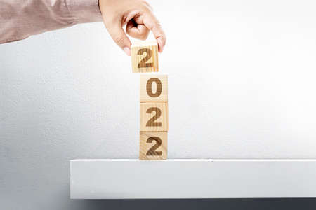 Hand put the 2022 on the stack of the wooden cube. Happy New Year 2022の写真素材